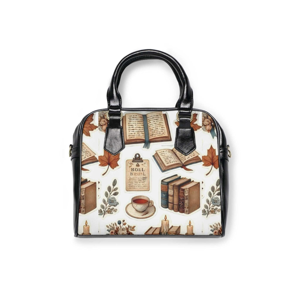 Black-handled shoulder handbag with book and autumn leaf print, removable adjustable strap, and zippered top closure.